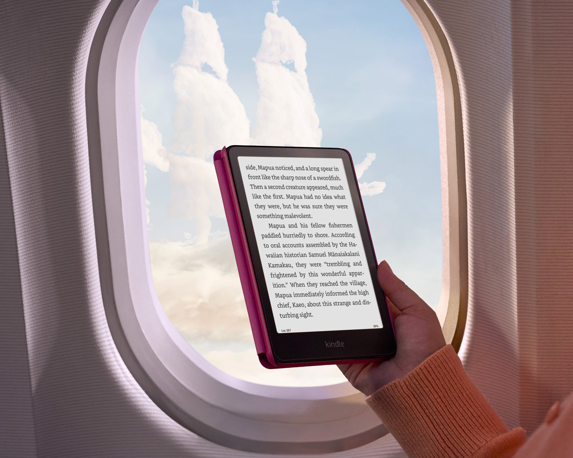 A reader on a plane holds Kindle Paperwhite in the window. Outside, the clouds are shaped like a pirate ship.